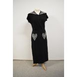 A 1930s black crepe dress having heavily beaded statement collar and pockets, with asymmetric