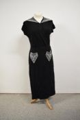 A 1930s black crepe dress having heavily beaded statement collar and pockets, with asymmetric