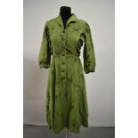 A 1950s vibrant pea green cotton day dress having atomic print and long sleeves, rusched panels to