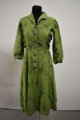 A 1950s vibrant pea green cotton day dress having atomic print and long sleeves, rusched panels to