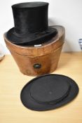 An antique leather cased top hat box containing a collapsible top hat and a top hat marked for J