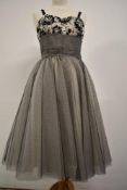 A 1950s evening dress having flocked velvet floral pattern to cream bodice and layers of black and