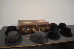 A vintage suitcase containing a selection of bowler hats and a top, top hat AF, suitcase having