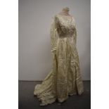 A late 1950s cream wedding dress and veil, dress having full length sleeves with buttons to cuffs