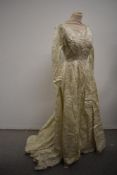 A late 1950s cream wedding dress and veil, dress having full length sleeves with buttons to cuffs