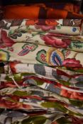 A box full of bright and bold rose patterned bark cloth curtains and similar fabrics.