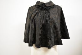 A Victorian black patterned silk or silk blend beaded cape with ribbon to neckline.