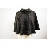 A Victorian black patterned silk or silk blend beaded cape with ribbon to neckline.