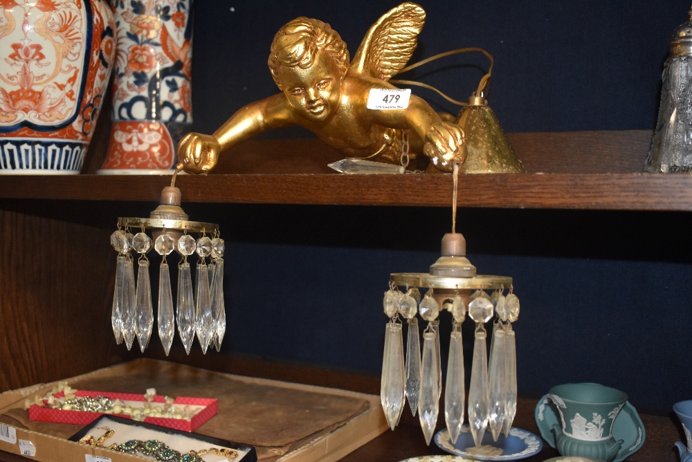 An early 20th century ceiling light in the form of a cherub holding two glass lustre droplet