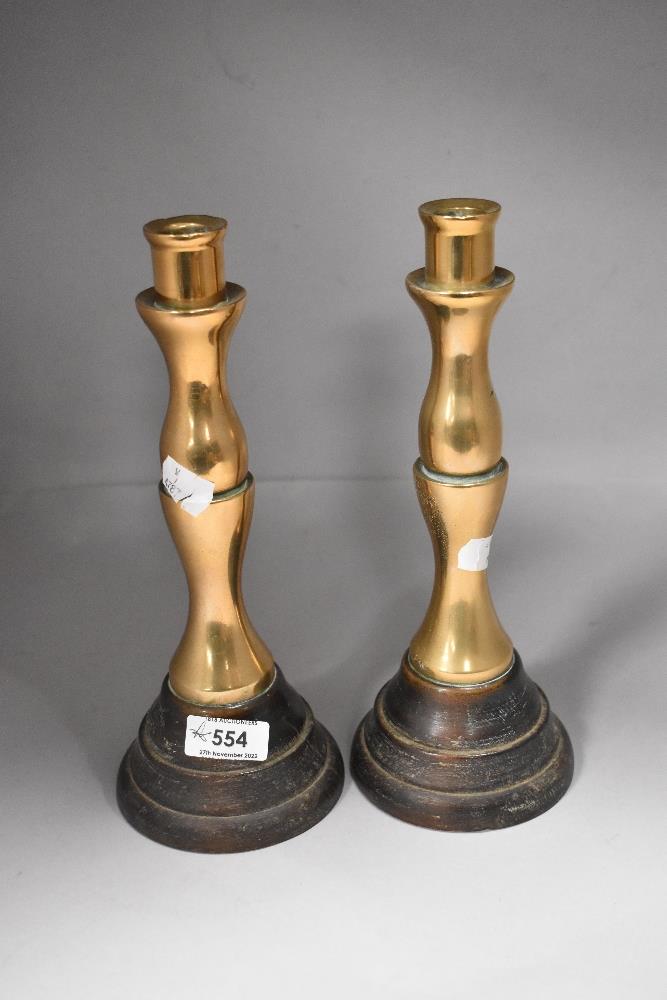 A pair of solid brass candlesticks on ebonised turned wood bases