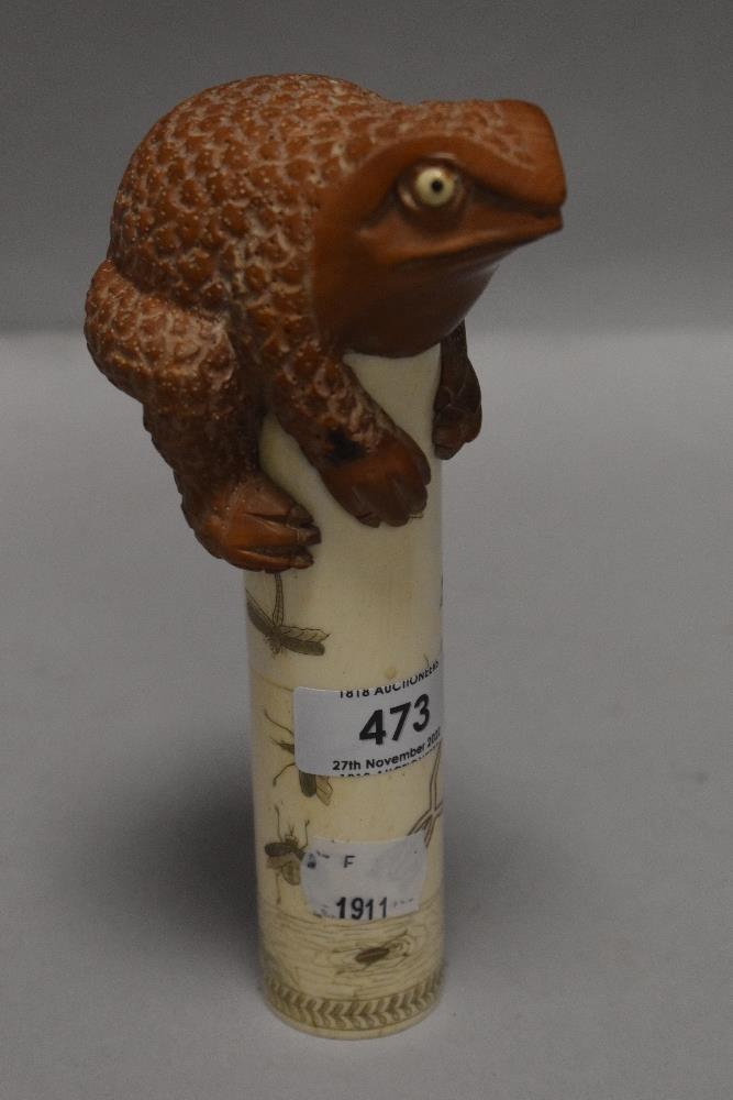 An unusual Chinese okimono style figure of a wooden carved toad perched atop a bone column carved
