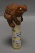 An unusual Chinese okimono style figure of a wooden carved toad perched atop a bone column carved