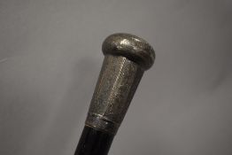 An early 20th century walking cane with ebonised shaft and white metal cap