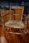 A Victorian elm rail back carver chair having rush seat