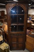 A good quality reproduction oak corner display with panelled cupboard to base