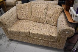 A modern settee in cream with maroon toned pattern