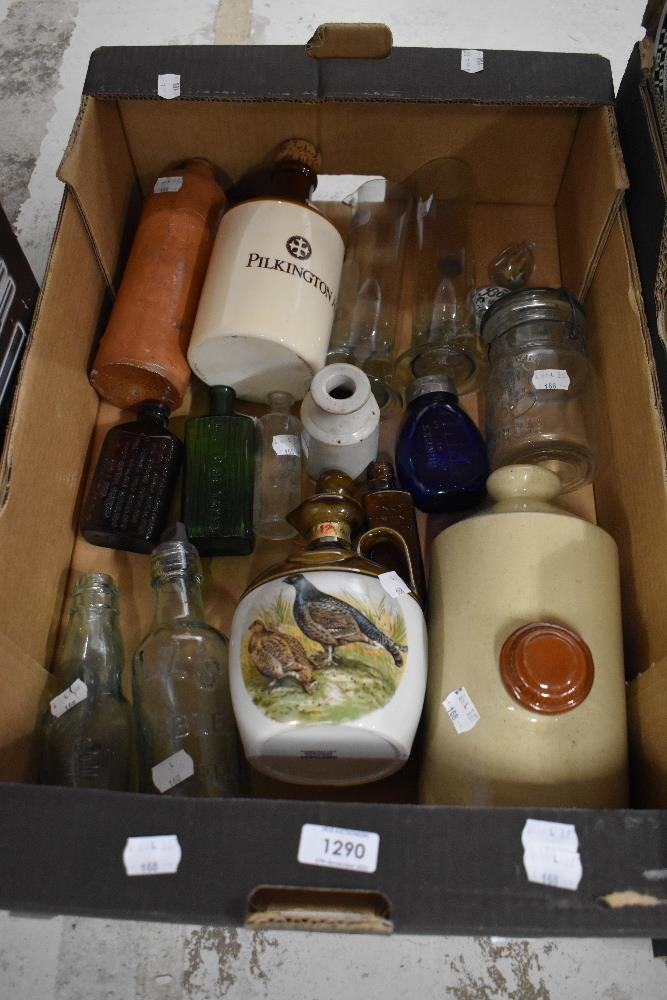 An assortment of vintage decanters and bottles including salt glazed foot warmer.