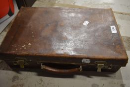 A small weathered leather suitcase containing a large selection of pens.