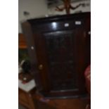 A Period oak corner wall cupboard having carved and poked decoration to door panel