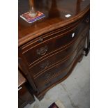 A reproduction serpentine chest of drawers, with brushing slide