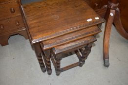 A reproduction solid oak nest of three tables having twist legs