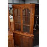 A reproduction yew wood corner display having cupboard under