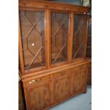 A reproduction yew wood bookcase having astral glazed display section over triple drawer and