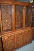A reproduction yew wood bookcase having astral glazed display section over triple drawer and