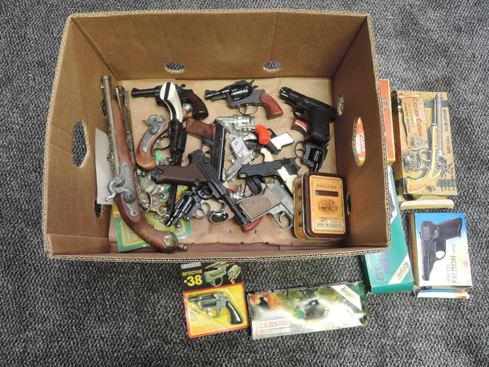 A box containing Toy replica Cap Guns including Flippy Python 357, Lone Star Luger, Captain Cutlass,