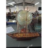 A wooden model Sailing Boat on stand along with a modern reproduction Globe also on stand