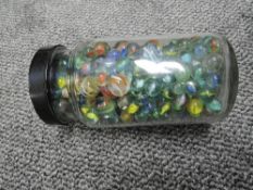 A plastic jar of mixed vintage Marbles including mixed sizes, various patterns and colours