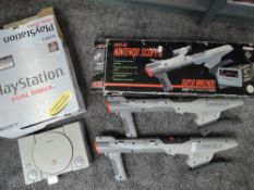 A Sony Playstation Duel Shock Console and two Super Nintendo Scope 6 Guns, with boxes