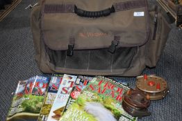 A Wychwood fishing bag containing two vintage reels and several copies of trout and salmon magazines