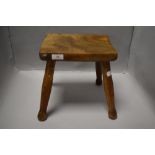An early 20th century traditional farm house milking stool with Elm wood top