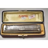 A cased Hohner 'The 64 Chromonica' harmonica/mouth organ