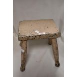 An antique farm house milking stool having painted oak frame