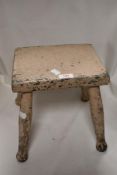 An antique farm house milking stool having painted oak frame