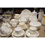 An antique partial tea service having white ground with gilt floral design, tea and coffee pots,