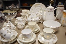 An antique partial tea service having white ground with gilt floral design, tea and coffee pots,
