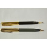 Two Parker 51 propelling pencils. One sage green and one brown with gold filled caps. The brown is