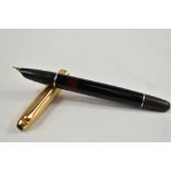 An Aurora twist fill fountain pen in black with transparent section to barrel with gold cap.