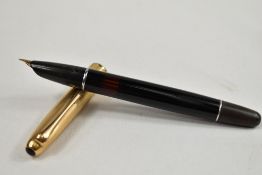 An Aurora twist fill fountain pen in black with transparent section to barrel with gold cap.