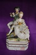 A German made porcelain lidded container with 18th century couple playing music in a Dresden style.