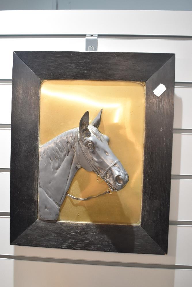 An early 20th century sculptural wall plaque with a pewter horse head on a brass background.