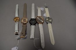 Five watches all having white straps.