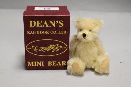 A 20th century miniature Dean's teddy bear with case and certificate having a light plush fur with