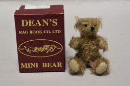 A 20th century miniature Dean's teddy bear with case and certificate having a light plush fur with