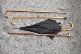 Three walking sticks one being in club form and a bamboo handle umbrella