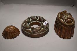Three antique copper jelly moulds one in ring form with fruit slice decoration, one cup cake size