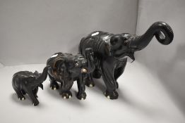 A family of three African elephants having carved hard wood bodies with an ebonised finish,